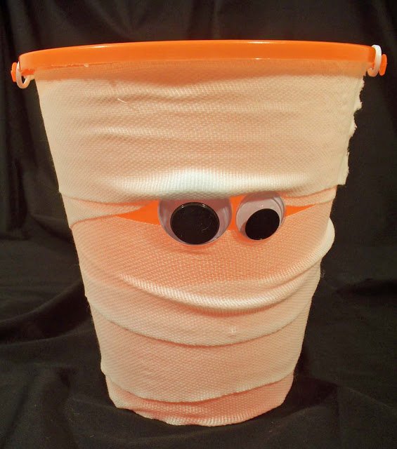 orange mummy bucket wrapped in gauze with big googly eyes. 