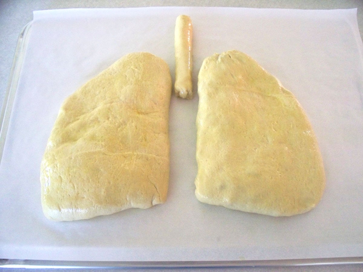 un-baked lung calzones on a parchment paper-lined baking sheet. 