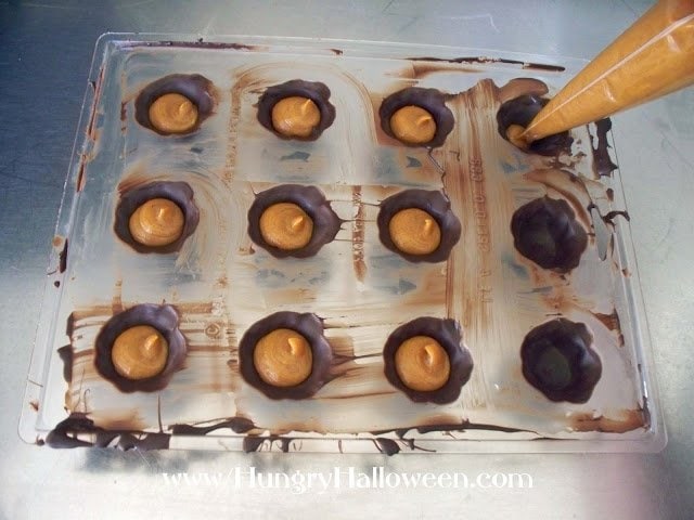 piping pumpkin ganache into the chocolate shells. 