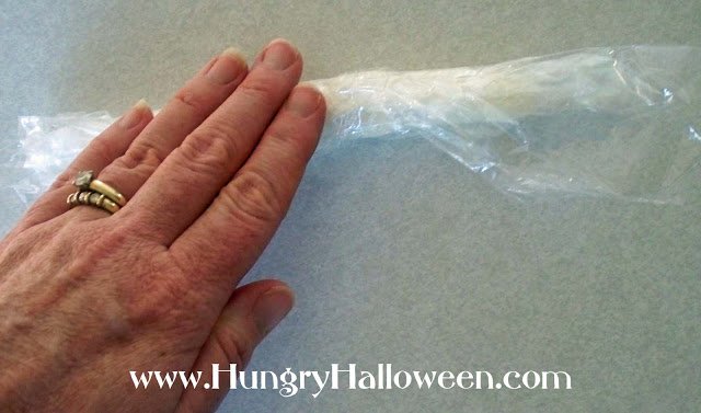 rolling cream cheese into a tube in plastic wrap.