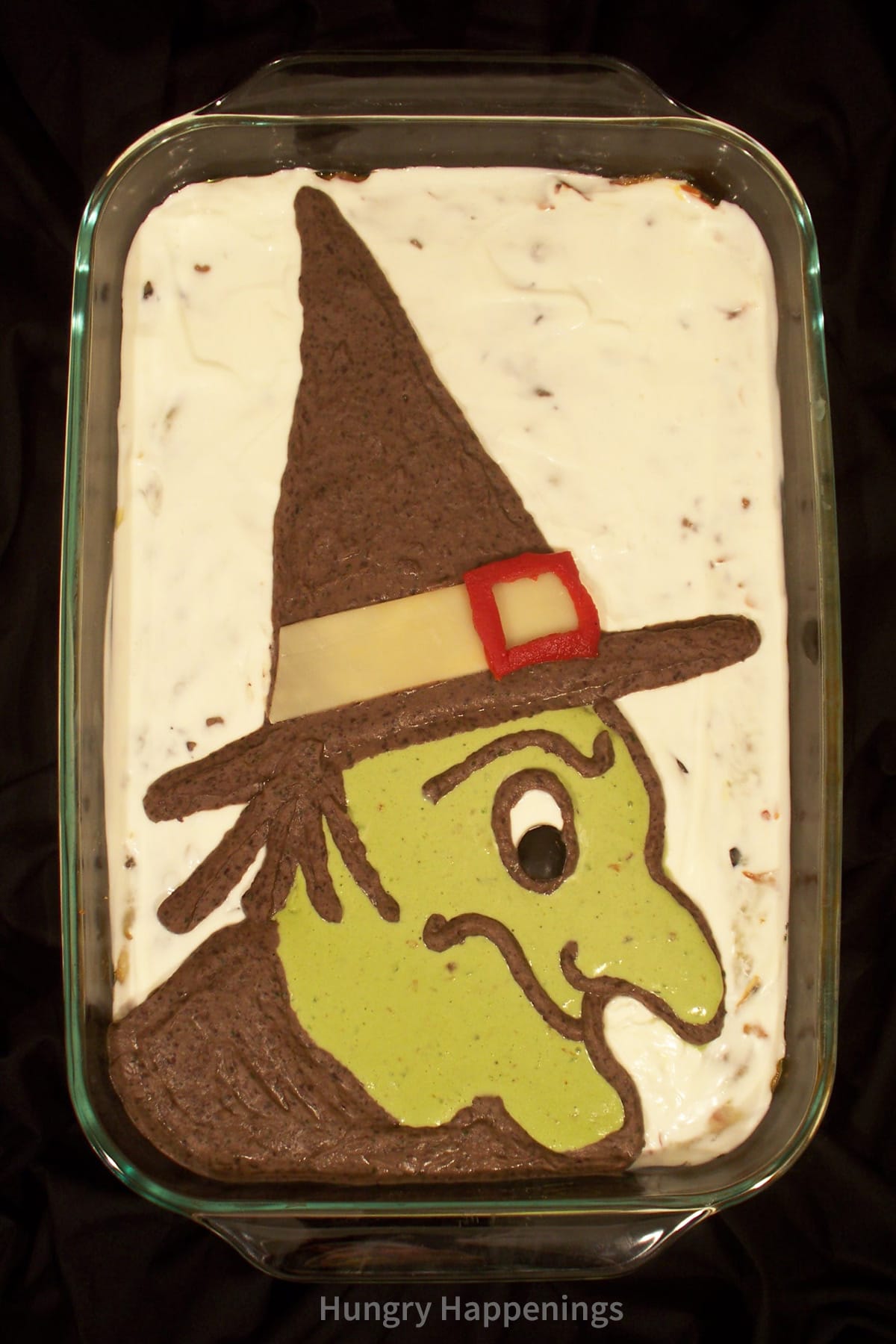 Halloween taco dip decorated with a guacamole witch.