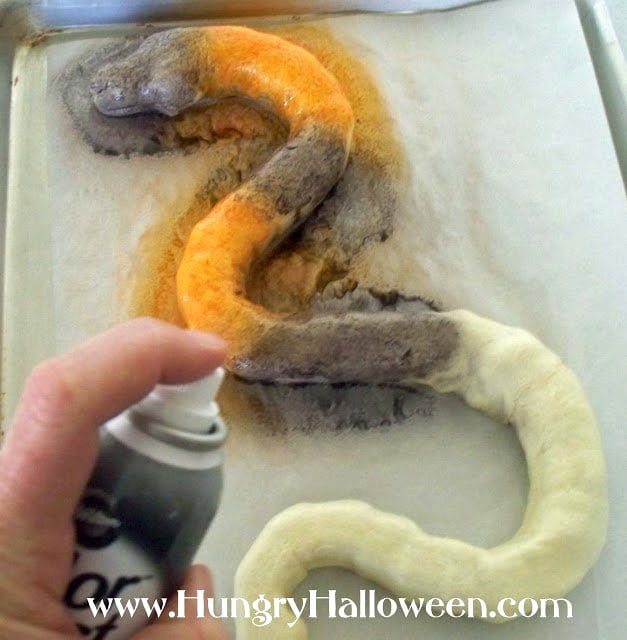 Use Wilton food coloring spray to create orange and black stripes on the crescent dough snake.