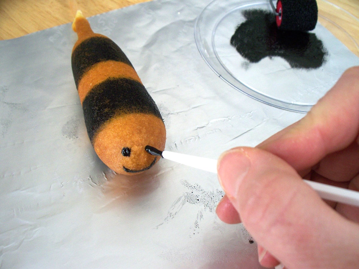painting the face onto a bumble bee corn dog.