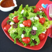 Mediterranean salad topped with heart-shaped tomatoes, olives, feta cheese, and tomato vinaigrette.