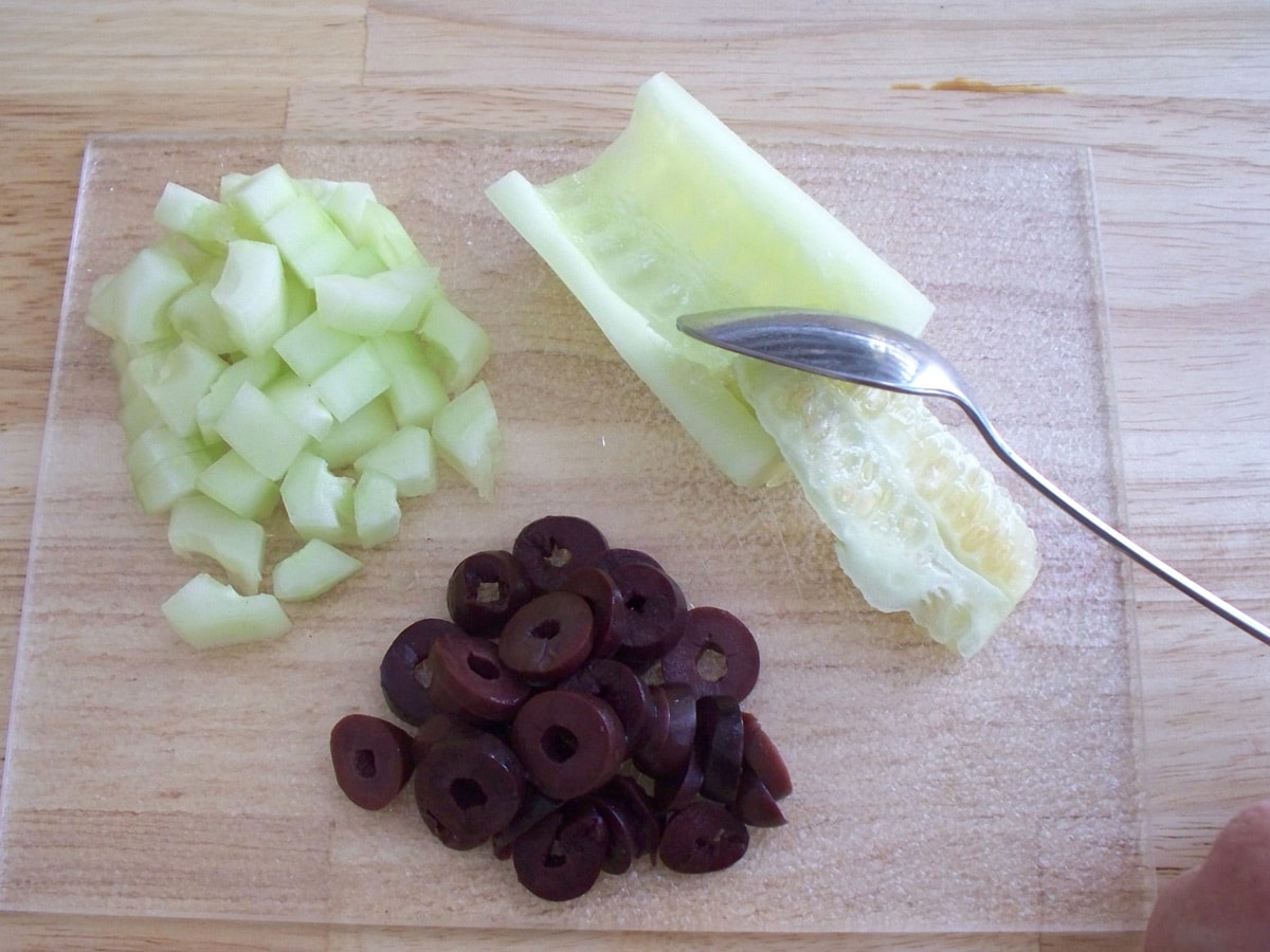 removing the seeds from a cucumber and sliced olives.