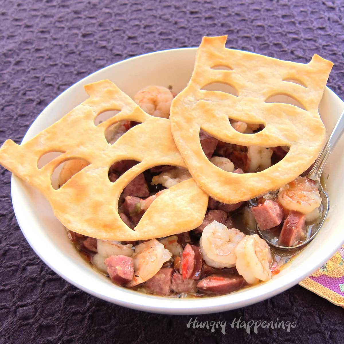 A bowl of hot Creole Sausage and Shrimp Gumbo is dressed up with pie crust masks for Mardi Gras.