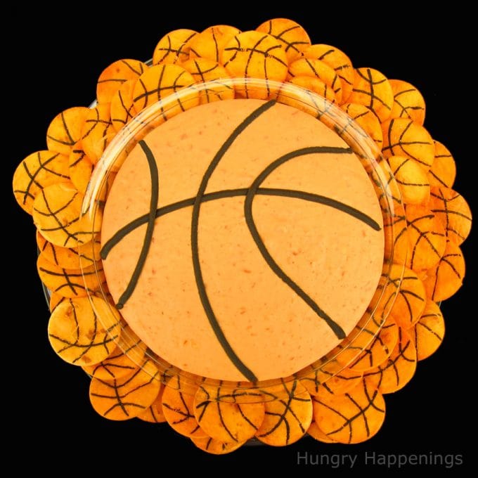 bowl of bean and cheese dip decorated to look like a basketball is served with basketball tortilla chips