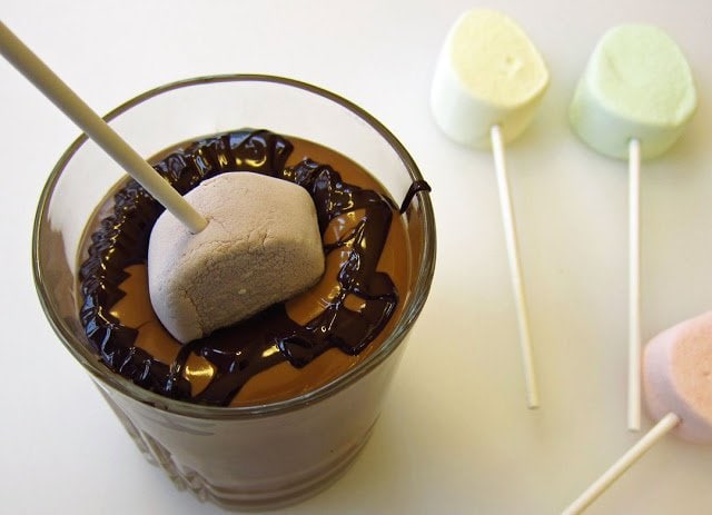dipping a marshmallow egg lollipop into the glass of milk and dark chocolate. 