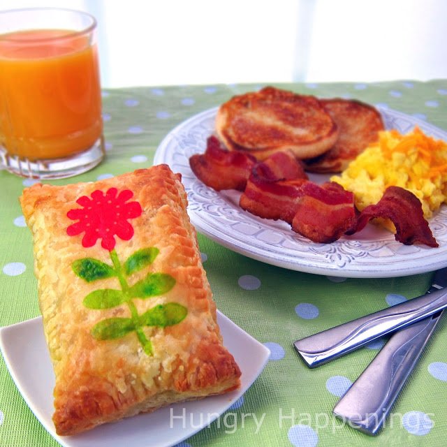 puff pastry stamped with a flower served with eggs, bacon, toast, and orange juice
