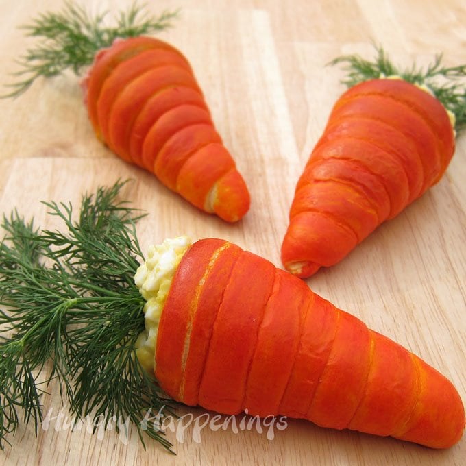orange-colored crescent roll carrots filled with egg salad and sprigs of fresh dill. 