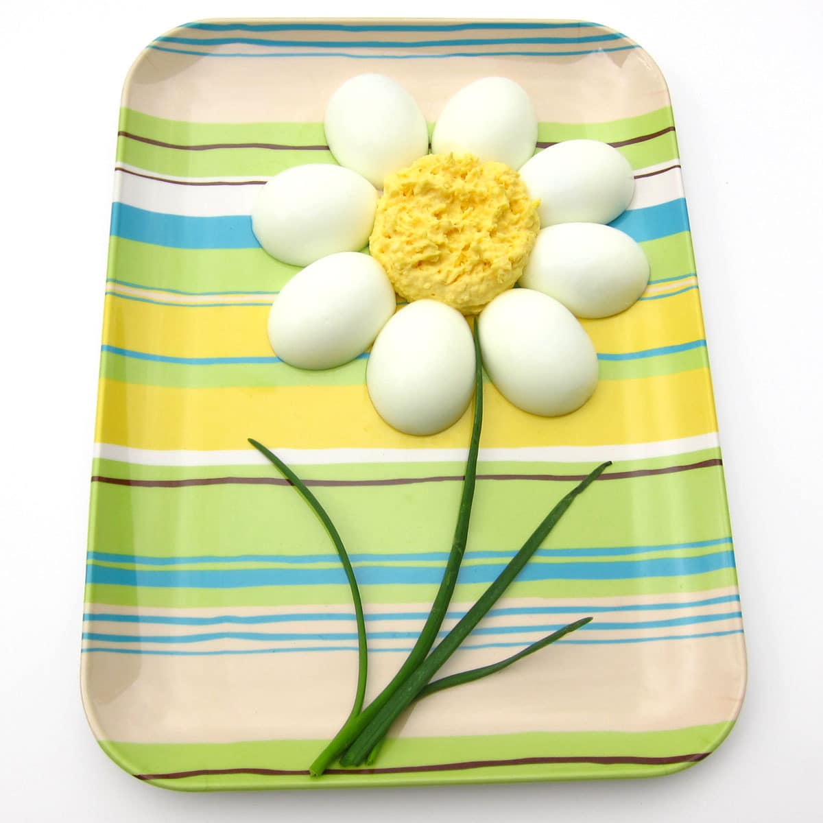 hard-boiled egg halves arranged around deviled egg filling forming a daisy. 
