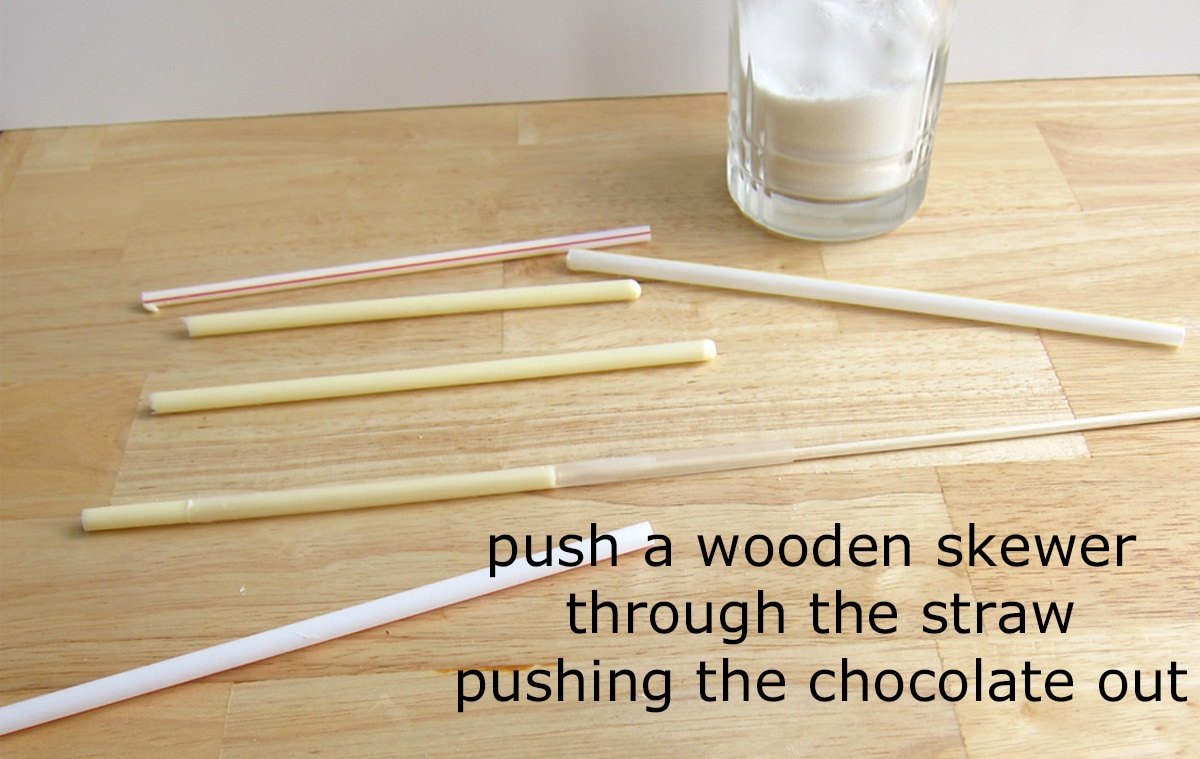 removing white chocolate chalk from straws using a wooden skewer.