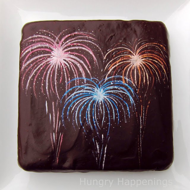 chocolate ganache frosted brownie decorated with colorful luster dust fireworks. 