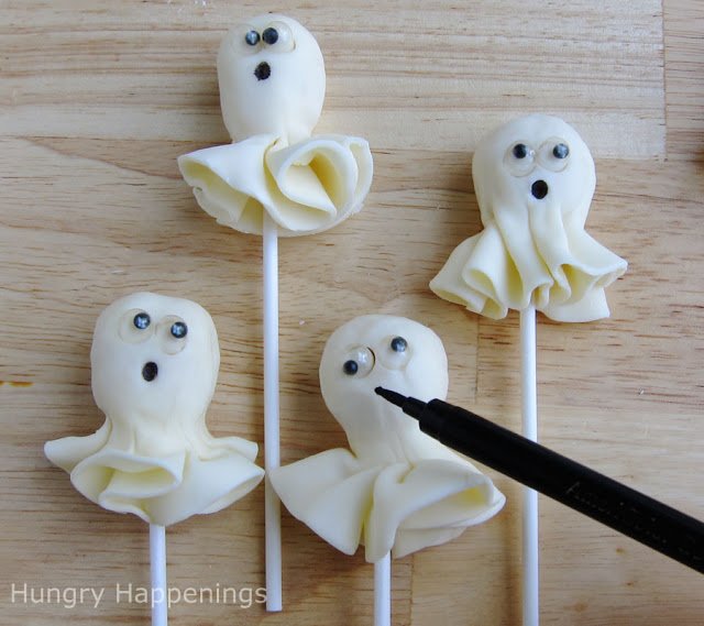 drawing mouths onto ghost lollipops using a black food coloring marker. 