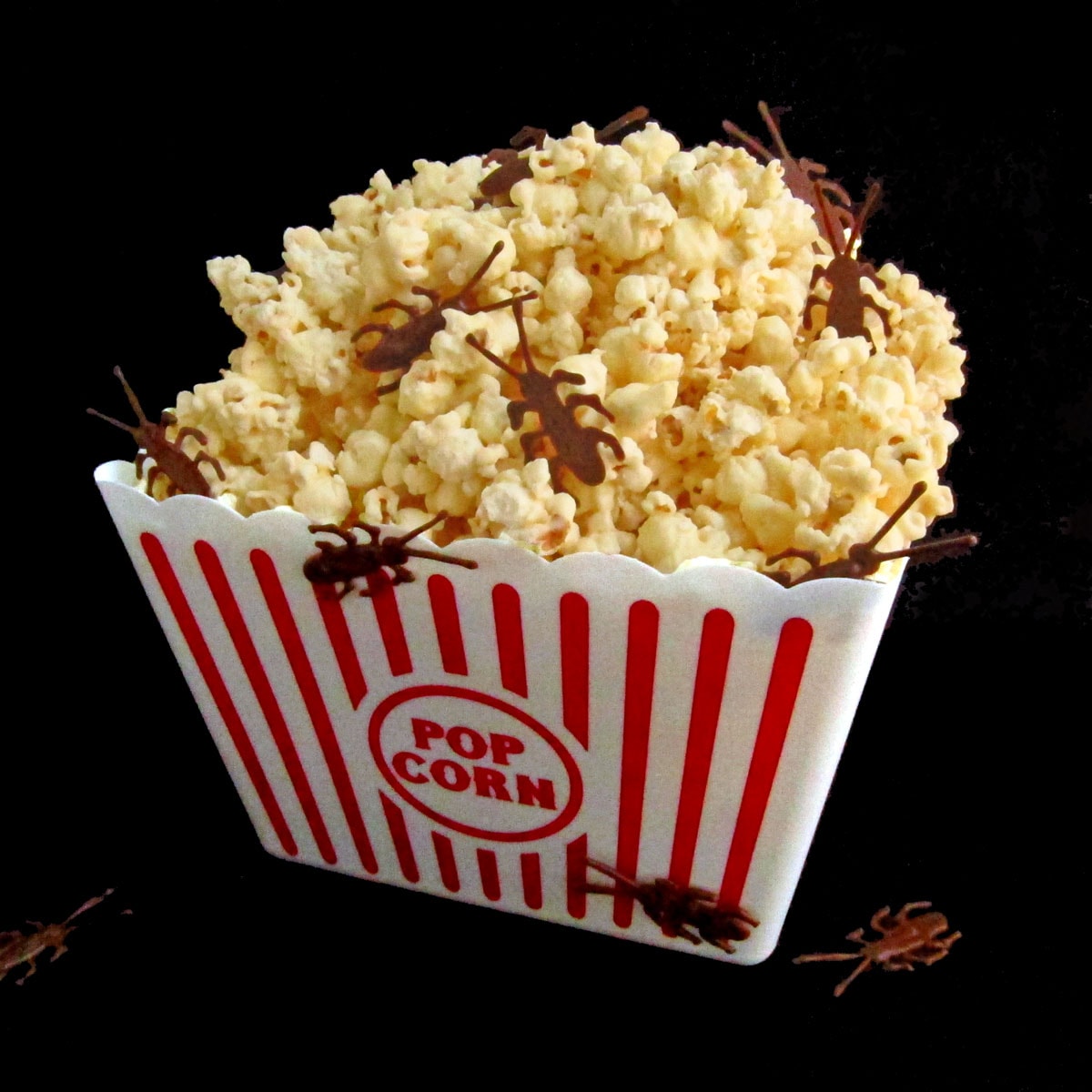 a big bucket of white chocolate popcorn filled with milk chocolate roaches for a Halloween snack