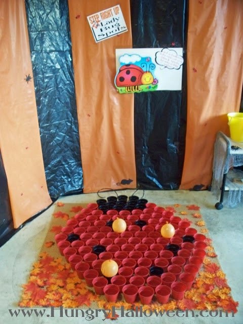 Halloween carnival game featuring a ladybug made out of red and black plastic cups and balloons. 