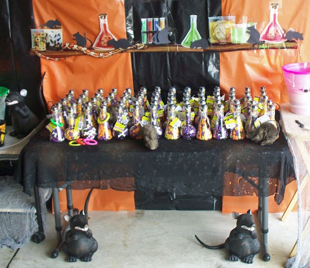 Halloween ring toss game with candy-filled beakers on a table surrounded by rats and other mad scientist decorations. 