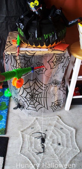 fly fishing game with a spider web on the ground with flies on top and a fishing pole with a spider attached.