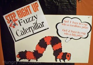 fuzzy caterpillar carnival game signs saying, "step right up - fuzzy caterpillar" and " Get 1 fuzz in cup and win a medium prize." and "Get 2 fuzz in cup win a big prize."