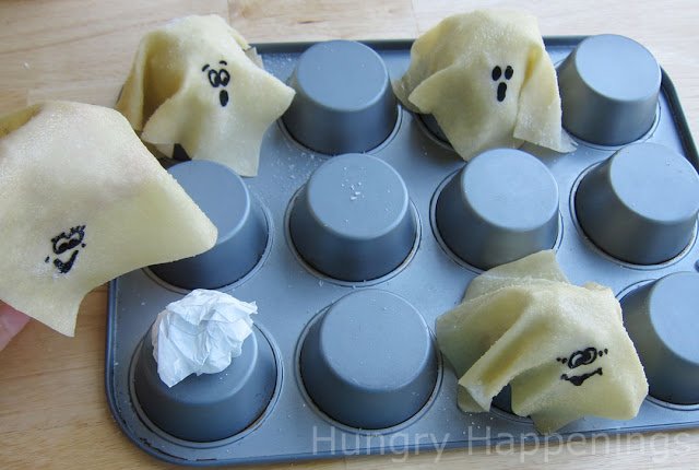 egg roll wrapper ghosts draped over an upside down cupcake pan. 