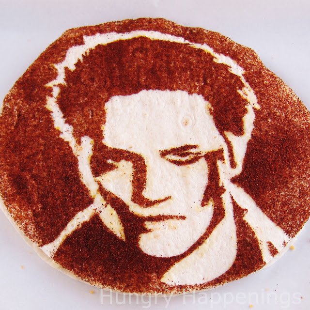 a tortilla decorated with chili powder using a stencil of Edward. 