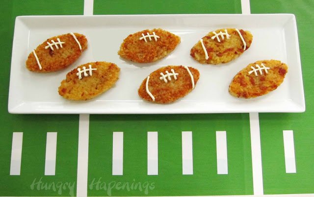Prosciutto and Asiago cheese rice cake footballs on a white plate on top of a football field tablecloth.