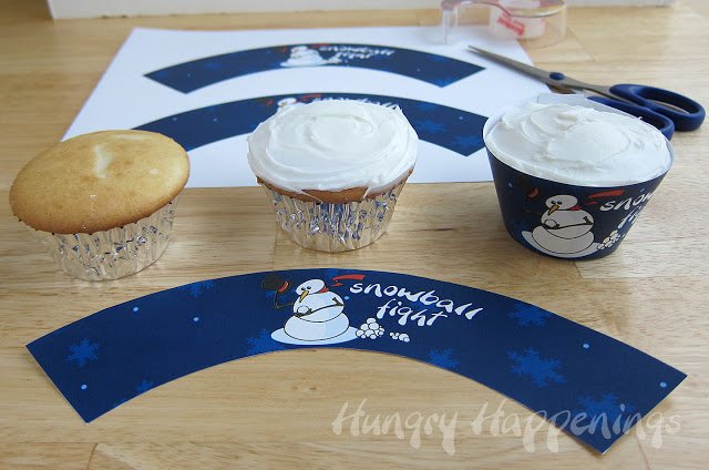 cupcakes frosted with white frosting and wrapped in snowball fight cupcake wrappers. 