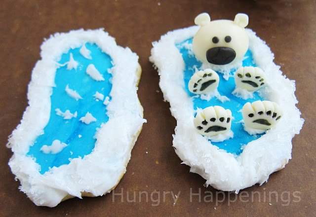 one ocean cookie decorated with frosting waves and one topped with a polar bear. 