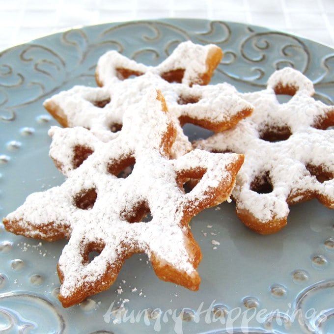 snowflake doughnuts topped with powdered sugar. 