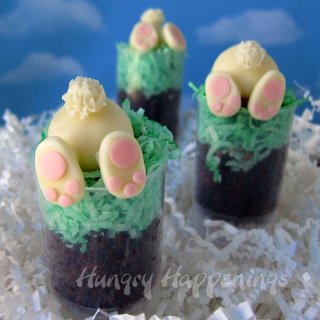 cute white chocolate bunnies burrowing down into green coconut grass and chocolate cake dirt. 