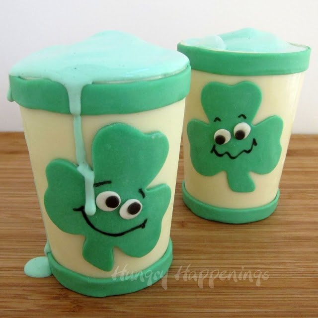 Green shamrock shakes spilling over the side of a smiling shamrock candy cup. 