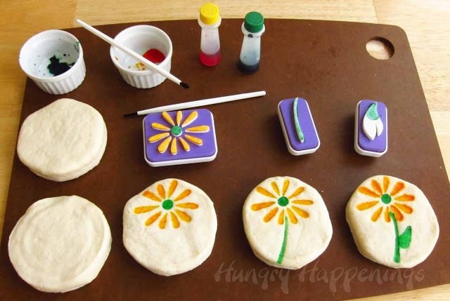 stamping biscuits using foam daisy stamps and food coloring.