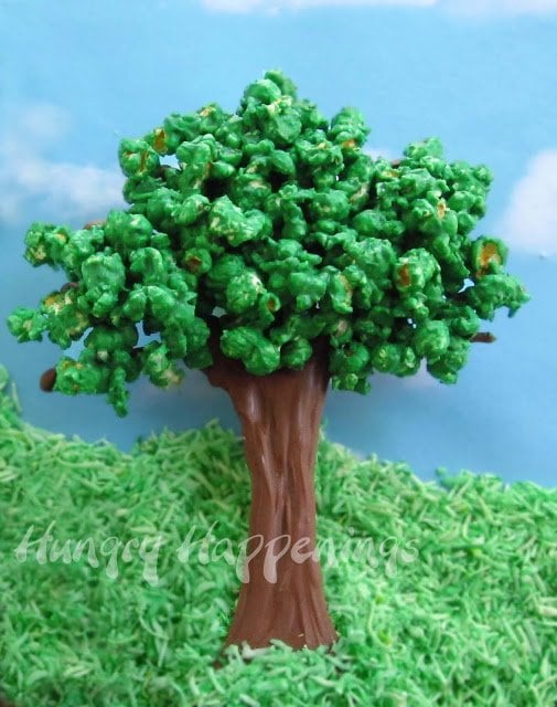 a chocolate popcorn tree in green coconut grass with a blue sky in the background. 