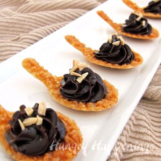 spoon-shaped almond nougatine cookies topped with chocolate ganache and slivered almonds
