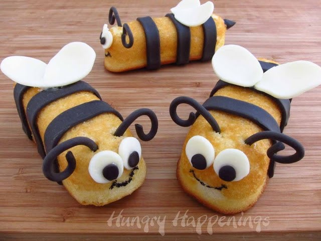 three snack cake bumble bees on a wooden cutting board. 