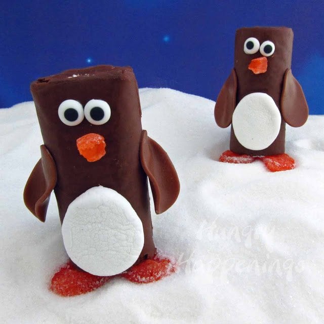 chocolate penguin cakes on a sugary snow covered ground with a blue star background. 