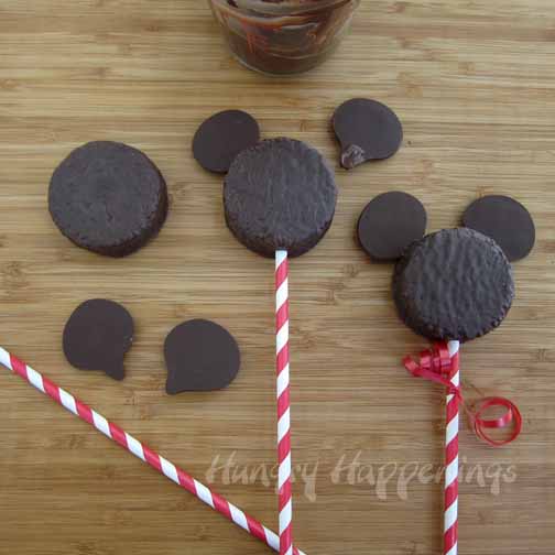 making Mickey Mouse Snack Cake lollipops with chocolate ears and paper straws. 