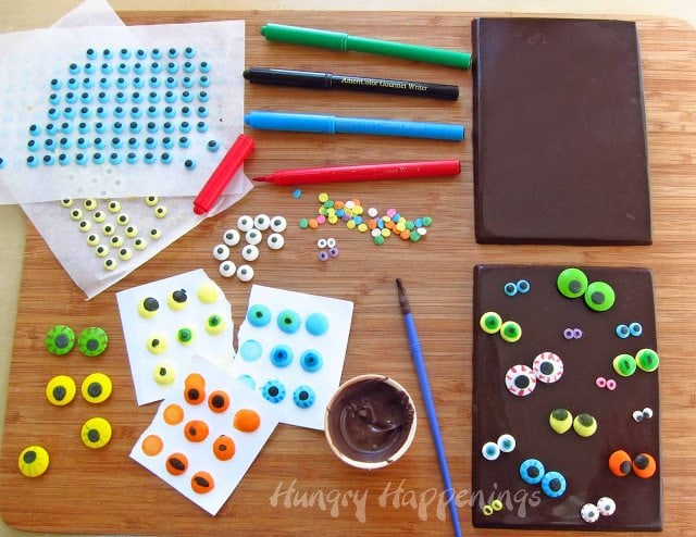 attaching candy eyes on a chocolate bar using melted chocolate and an assorted candy eyes. 