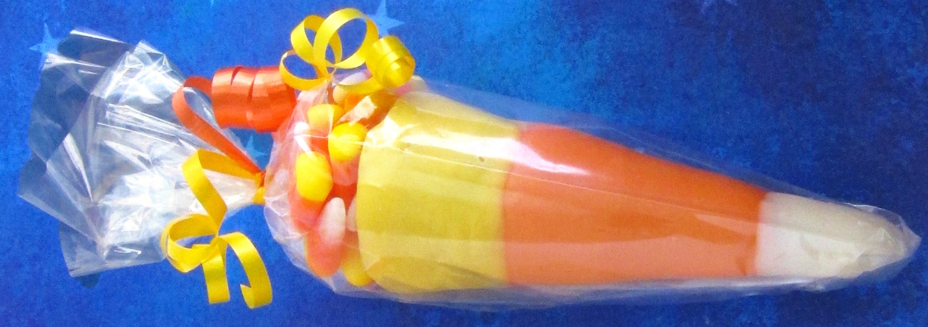 Candy Corn Cones filled with candy corn wrapped in clear cellophane tied with yellow and orange ribbons. 