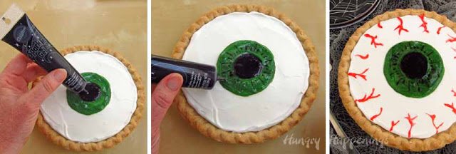 decorating an eyeball on a pie using black gel to create the pupil inside a green iris.