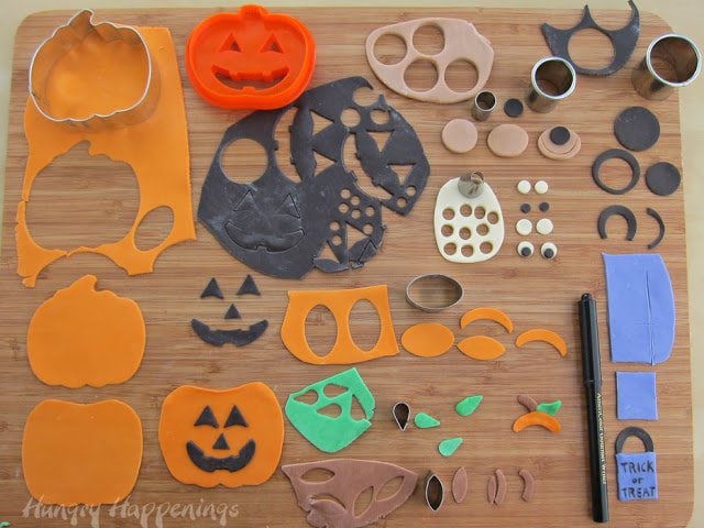 making pumpkin costumes using orange jack-o-lanterns, green leaves, brown stems, black faces, white eyes, and blue trick or treat bags.