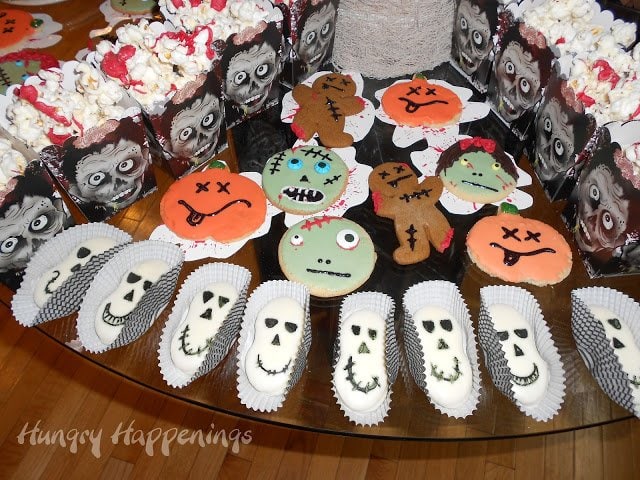 skull cookies and zombie cookies on a Halloween dessert table. 