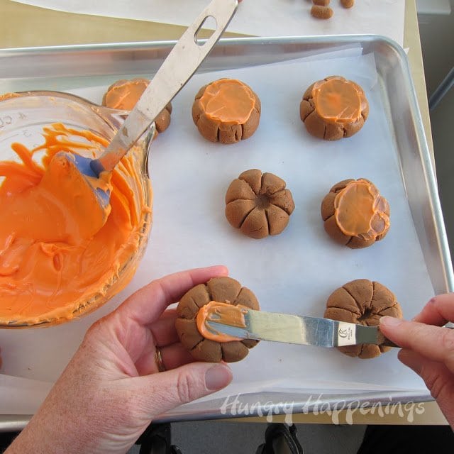 spreading a thin layer of orange candy melts onto the bottom of the chocolate caramel fudge pumpkins. 