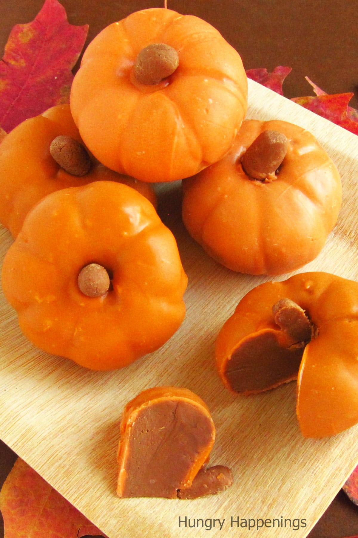 caramel chocolate fudge pumpkins piled on a bamboo plate. 