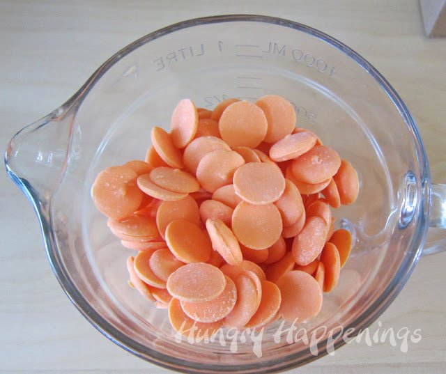 a microwave-safe bowl filled with orange candy melts wafers. 