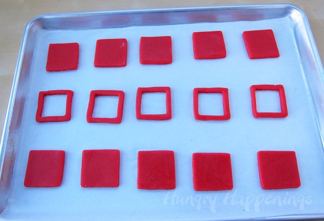 square red cookie dough on a parchment paper-lined baking sheet and square cookies with a square cut out of the center. 