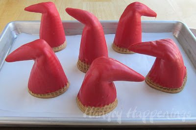 red candy-coated sugar cone Santa hats on a parchment paper-lined baking sheet. 