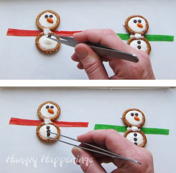 adding three mini chocolate chip buttons to the white chocolate pretzel snowmen. 
