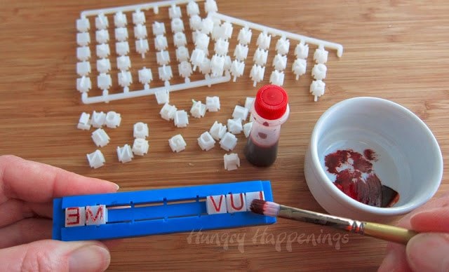 brushing red food coloring over clay text embossing stamps.
