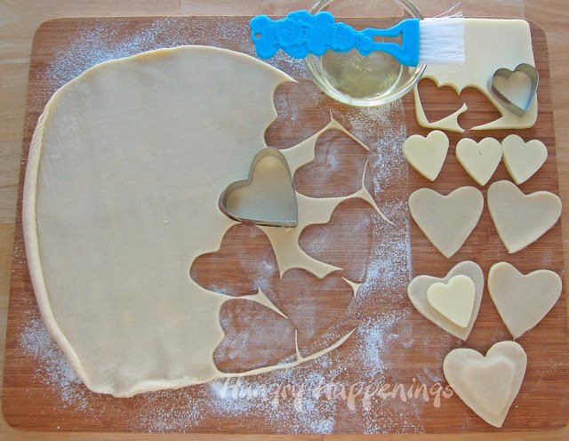cut pie crust and mozzarella cheese using a heart cookie cutter then, sandwich cheese in between two pie crust hearts
